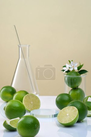 Front view of transparent podium for display cosmetic of lime extract with lab glassware, flower, leaves and fresh limes on brown background. Natural cosmetic research concept with vitamin C
