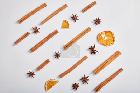 Photo for Minimal art background with cinnamon sticks, anise and dried orange slices on white background. Advertising photo for product of natural herbal extract. Top view, flat lay. - Royalty Free Image