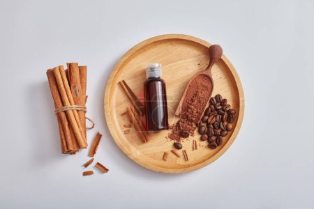 Photo for Mockup scene for product of herbal extract with brown bottle without label, cinnamon sticks and powder, coffee on wooden dish, isolated on light background. Top view, flat lay, copy space. - Royalty Free Image