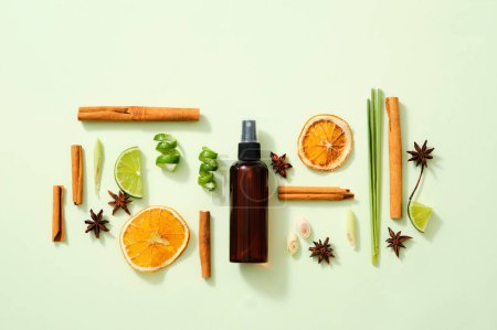 Photo for Scene mockup for product of natural flavoring extract with brown bottle without label, cinnamon sticks, illicium verum, lemon slice, dried orange slices and lemongrass on light background. Top view - Royalty Free Image