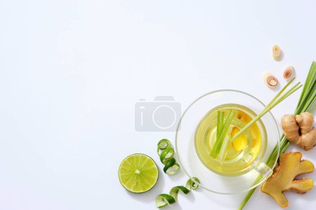 Photo for Top view of ginger tea with fresh lemongrass, lemon slice, ginger root and grapefruit peel on white background. Space for text and design. Healthy herbal, anti aging, reduce stress, haircare - Royalty Free Image