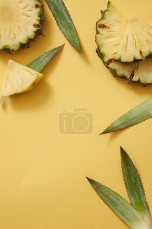 Cadre de beauté avec tranches d'ananas frais (Ananas comosus) et feuilles vertes décorées sur fond jaune. Espace vide pour le texte et le design. Concept de beauté naturelle, produit de l'extrait d'ananas.