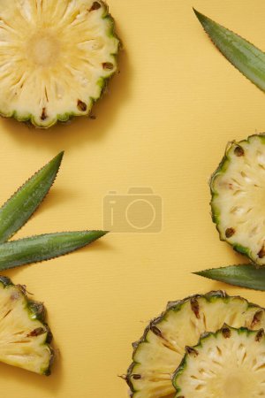 Photo for Tropical fruit pineapple with fresh slice and leaves on yellow background. Blank in middle for text and design. Scene for advertising product with ingredients from pineapple. Top view, copy space. - Royalty Free Image