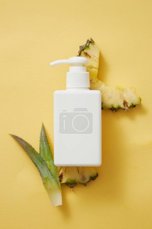 Photo for Mockup body lotion, sunscreen or shampoo container with pump dispenser. Cosmetic of pineapple extract. Pineapple slices and leaves on yellow background. Top view, natural extracts medical skin care - Royalty Free Image
