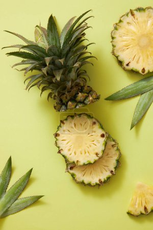 Téléchargez les photos : Fond créatif avec tranche d'ananas frais (Ananas comosus), feuilles et tige d'ananas décorées sur fond vert. Scène pour la publicité de produits avec des ingrédients de l'ananas. Espace de copie - en image libre de droit