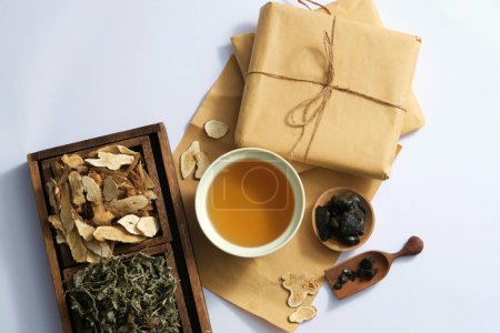 Photo for Top view of medicine cup, medicine package and dried herbs on wooden tray on light background. Collection of herbs to prepare a tonic drink, traditional medicine from China - Royalty Free Image
