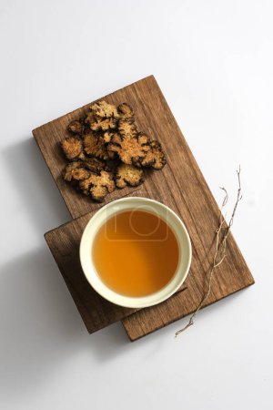 A wooden tray containing Ligusticum striatum and medicine cup on light background. According to traditional Chinese medicine, ligusticum striatum works treatment of headaches, menstrual disorders