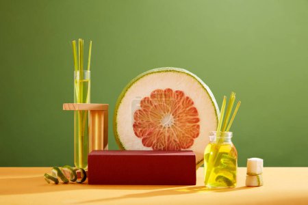 Photo for Front view of empty podium for display cosmetics with fresh pink pomelo slice, bottle and test tube containing lemongrass essential oils on green background. Space for cosmetic product mockup. - Royalty Free Image