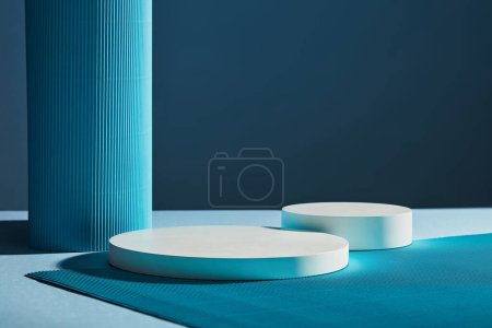 Téléchargez les photos : Vue de face de deux podiums blancs ronds vides sur fond bleu foncé. Fond d'art minimal avec espace de copie pour la présentation de produits cosmétiques - en image libre de droit