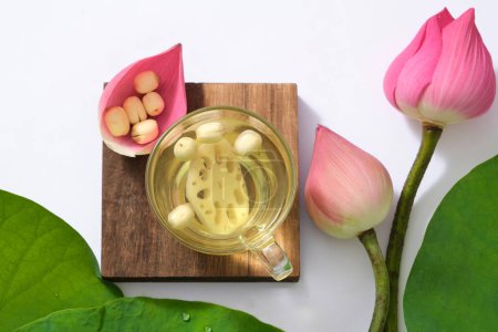 Photo for Top view of set of lotus seed tea on wooden podium, fresh lotus buds and green leafs on white background. This food helps to be healthy, sleep well. (Nelumbo nucifera) - Royalty Free Image