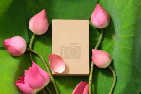 Téléchargez les photos : Vue de dessus du podium vide entouré de bourgeons de lotus rose frais et de feuilles vertes. Espace de produit d'affichage ou cosmétique avec concept de fleur. Pose plate. (Nelumbo nucifera) - en image libre de droit