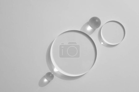 Top view, flat lay of transparent podiums and crystal ball on white background. Blank minimal design concept. Space for product presentation, advertising photo, mockup. Copy space.