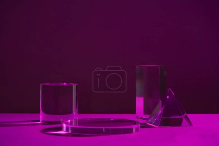 Foto de Escaparate de productos con un podio de cristal y una textura acrílica decorada en un colorido fondo ombre negro y púrpura. Soporte geométrico transparente para cosméticos. - Imagen libre de derechos