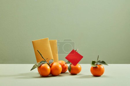 Téléchargez les photos : Vue de face des fruits (mandarines) et enveloppes chanceuses sur fond vert. Espace vide pour le texte. Nouvel an lunaire chinois. - en image libre de droit