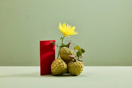 Foto de Manzana natillas, crisantemo y sobre rojo sobre fondo verde. Vista frontal. Fruta asiática. Año nuevo chino. - Imagen libre de derechos