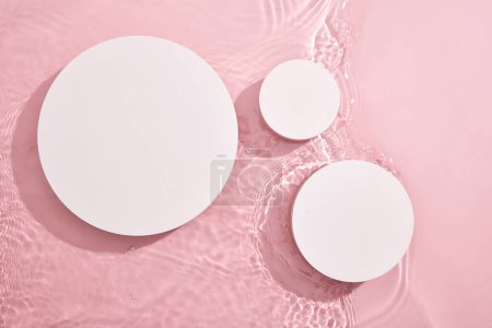 Photo for Top view of three white circular empty podiums, set on a pink background with water and tiny ripples. Blank space for display products. Blank minimal design concept. - Royalty Free Image