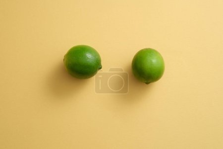 Foto de Sobre un fondo beige, dos cal están aislados. Espacio en blanco para mostrar el producto de belleza extraído de Lime (Citrus aurantiifolia). Copiar espacio - Imagen libre de derechos