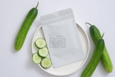 Photo for White mask package put on a round dish decorated with Cucumber slices. Cucumber (Cucumis sativus) mask is used to improve and cool sunburned skin - Royalty Free Image