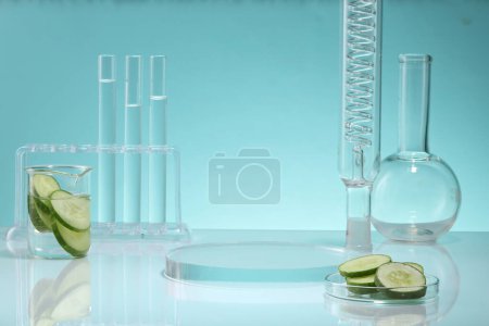 Photo for Research content with beaker and petri dish containing Cucumber slices and other laboratory glassware. Round transparent podium displayed. Cucumber (Cucumis sativus) has anti-inflammatory properties - Royalty Free Image