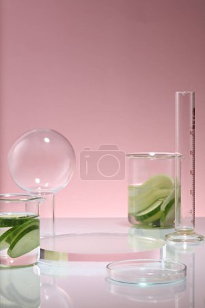 Photo for Over a purple background, a transparent podium in round shape displayed with two beakers of Cucumber and some glassware. Cucumber (Cucumis sativus) is rich in vitamin C - Royalty Free Image
