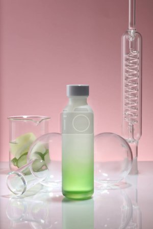 Photo for A gradient white and green bottle placed on mirror table with a condenser, a beaker of Cucumber and flasks. Mockup of skin care product extracted from Cucumber (Cucumis sativus) - Royalty Free Image