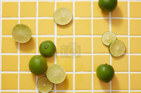 Minimal scene of several Lime and Lime slices are decorated on yellow mosaic tiles background. Empty space for cosmetic product presentation of Lime (Citrus aurantiifolia) extract