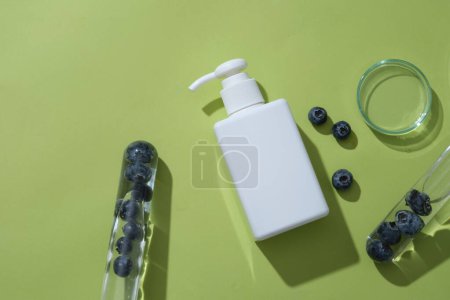 Photo for Test tubes containing blueberries inside, arranged with glass petri dish and unlabeled pump bottle. Blueberry help exfoliate dead skin cells thanks to high levels of salicylic acid present in it - Royalty Free Image