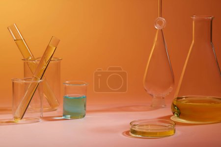 Foto de Fondo naranja con muchos artículos de vidrio de laboratorio llenos de líquido amarillo y azul en el interior. Concepto pruebas de laboratorio e investigación - Imagen libre de derechos
