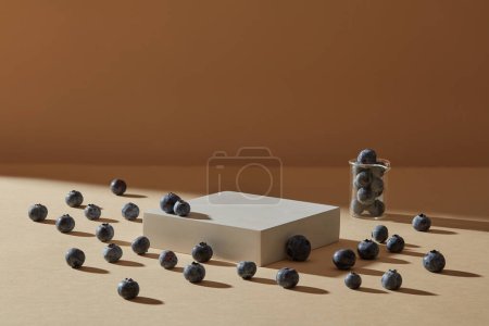 Many blueberries are arranged on brown background with soft shadow. Empty square podium for natural beauty product presentation of Blueberry (Vaccinium Corymbosum) extract