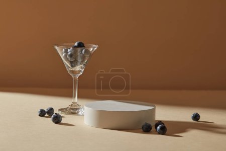 Photo for A cocktail glass filled with blueberries displayed with a white round podium. Salicylic acid in Blueberry kills all those acne-causing bacteria that cause skin to break out - Royalty Free Image