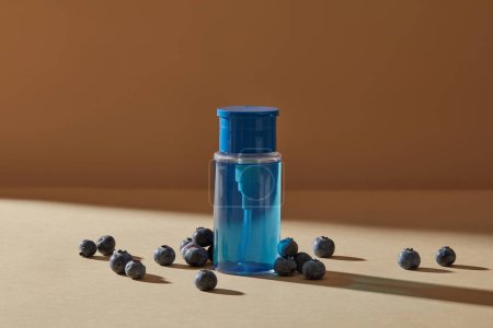 Photo for A push down pump dispenser bottle decorated with blueberries on brown background. Blueberry (Vaccinium Corymbosum) extract have a calming and soothing effect on the skin - Royalty Free Image