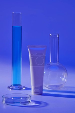 Blank label white tube arranged with a tube, petri dish and flat-bottom florence flask. Cosmetic product mockup with laboratory concept