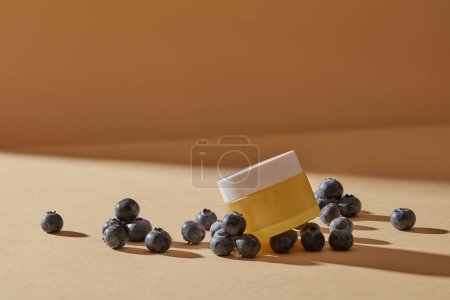 Unlabeled jar is put on several blueberries with shadow. Blueberry (Vaccinium Corymbosum) is high in anthocyanin, which may support collagen synthesis