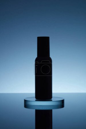 Foto de Concepto de luz trasera con una botella de envase cosmético colocada en un podio redondo transparente de vidrio en el espejo con reflexión. Maqueta del producto - Imagen libre de derechos