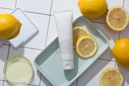 A hand mirror, a petri dish of Lemon essential oil and a tray of white tube and Lemon slices are decorated on mosaic tiles background. Lemon (Citrus limon) has antifungal and antimicrobial properties
