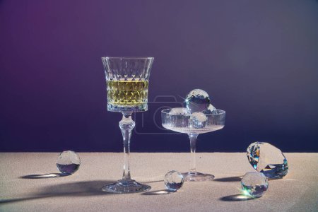 Foto de Una copa de vino de champán o bebida amarilla exhibida con una copa que contiene esfera de diamante sobre fondo oscuro - Imagen libre de derechos