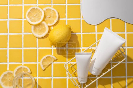Foto de Dos tubos cosméticos dentro de una cesta, decorados con varias rodajas de limón, un vaso de agua y un espejo. Limón (Citrus limon) tiene cualidades astringentes debido a su nivel ácido - Imagen libre de derechos