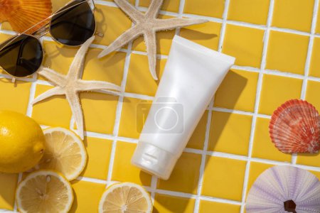 Beauty cosmetic tube arranged with Lemon slices, starfishes, sunglasses and some types of seashells. Cosmetic product extracted from Lemon (Citrus limon) can brighten your skin tone