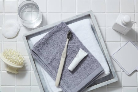Eine Zahnbürste mit Mini-Röhrchen auf Handtüchern mit Spiegel, Pumpenflasche, Wasserglas, Baumwollkissen und Kopfhautmassagebürste. Aloe vera (Aloe barbadensis miller) ist wirksam bei der Behandlung von Gingivitis