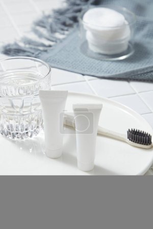 Eine runde Schüssel mit einem Glas Wasser, einem nicht etikettierten Schlauch und einer Zahnbürste darauf. Bio-Produkt-Attrappe. Aloe Vera (Aloe barbadensis miller) hilft, schädliche Bakterien im Mund zu beseitigen