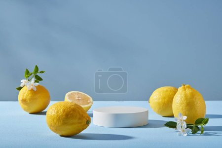 Minimale Szene eines weißen Podests in runder Form, verziert mit mehreren Zitronen und kleinen weißen Blumen mit Frontansicht. Hellblauer Hintergrund. Biologische Produktwerbung für Zitronen- (Zitrus-) Extrakt