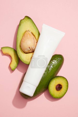 Photo for A white tube placed on Avocado slices. Blank label for beauty products advertising of Avocado extract. Avocado (Persea americana) has vitamin C and E helps to protect skin from oxidant damage - Royalty Free Image