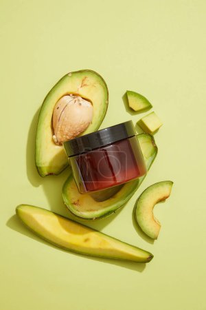 Flat lay of a jar without label displayed with Avocado slices. Branding mockup. Avocado (Persea americana) is a great source of biotin, help prevent brittle hair and nails