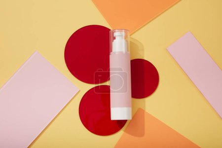 Foto de Botella bomba rosa con tapa transparente colocada sobre unas láminas acrílicas redondas en color rojo. Paquete cosmético maqueta de recogida de crema, espumas, loción - Imagen libre de derechos