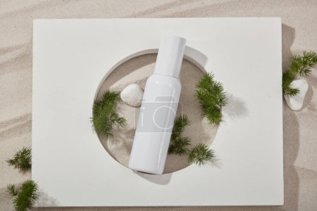 Beauty cosmetic container displayed with green leaves and gravels. Abstract podium from natural materials product presentation on a sandy background