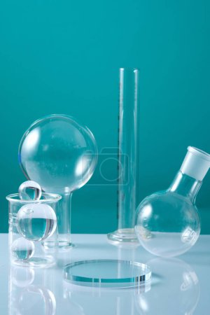 Photo for A glass transparent podium in round shape arranged with a beaker containing some balls on light blue background. Research production of cosmetics - Royalty Free Image