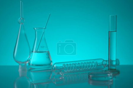 Photo for Over a blue background, erlenmeyer flask, a tube with spiral pipe inside, test tube and a petri dish are arranged. Laboratory experience and research - Royalty Free Image