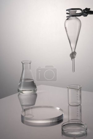Photo for Back light concept with transparent laboratory glassware containing liquid and a circle podium. Blank space to display product or goods - Royalty Free Image