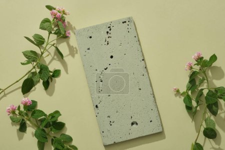 Un podio de piedra vacío en color gris decorado con algunas flores de la cámara Lantana sobre un fondo claro. Espacio en blanco para la promoción de productos. Concepto natural