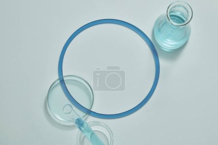 Foto de Sobre fondo blanco se disponen un tubo de ensayo, una placa de Petri de vidrio y un matraz erlenmeyer lleno de líquido azul. Área vacía para la presentación del producto - Imagen libre de derechos